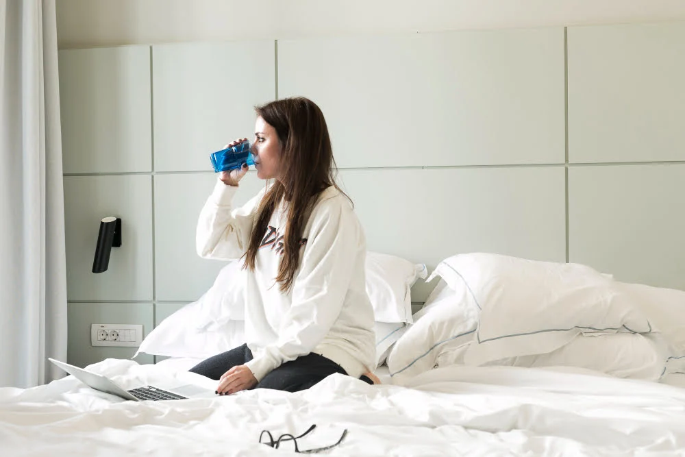 woman drinking water on bed