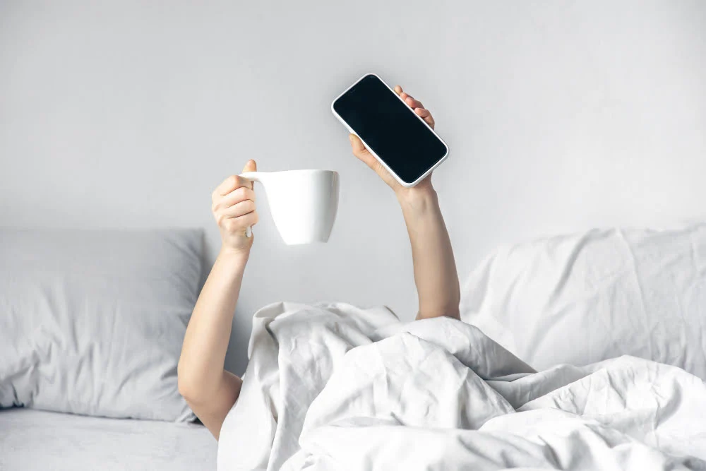 A woman lies in bed with a smartphone